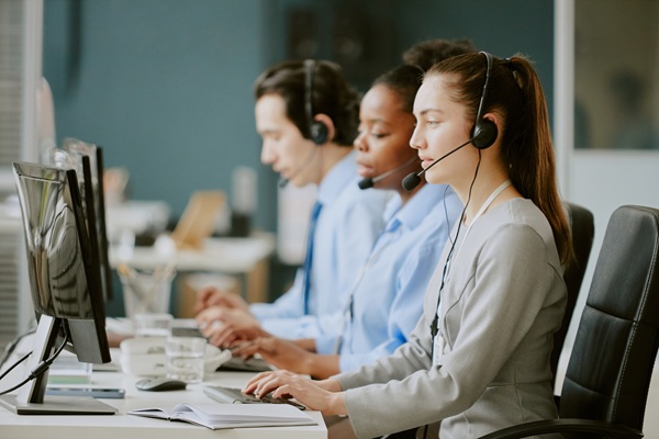 Young,Biracial,Call,Center,Operators,Sitting,At,Work,Desk,With