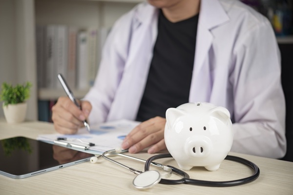 Doctor,With,Stethoscope,And,White,Piggy,Bank,On,Desk,,Concepts