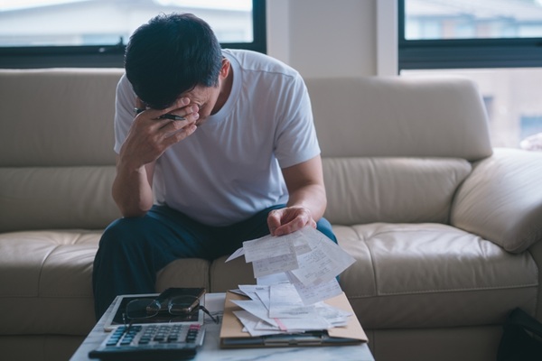 Stressed,Man,Reviewing,Bills,And,Expenses,At,Home,While,Managing
