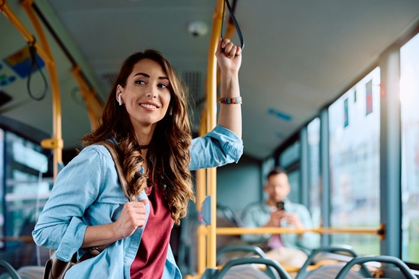 Young,Smiling,Woman,Holding,Onto,A,Handle,While,Traveling,By