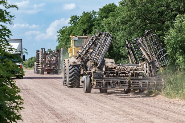 Agricultural,Machinery,Transporting,Disk,Harrows,Along,A,Rural,Dirt,Road.