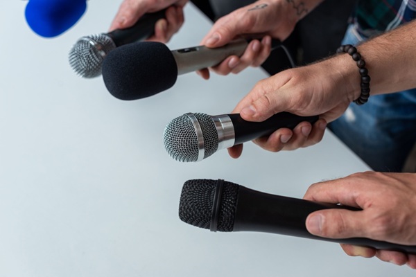 Close-up,Of,Four,Hands,Holding,Different,Microphones,,Suggesting,A,Press