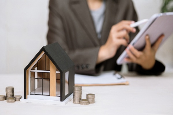 A,Model,House,And,Stacks,Of,Coins,Sit,On,A